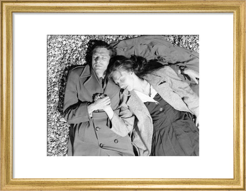 A couple lying together on Brighton Beach c. 1955