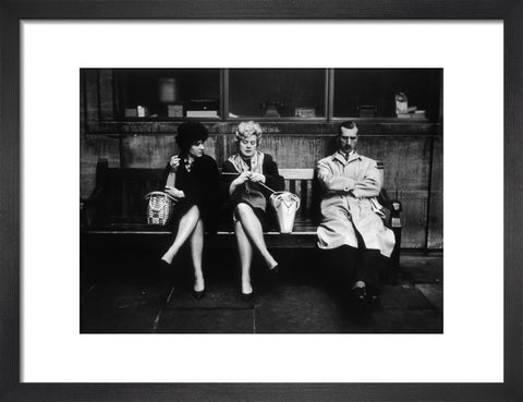 Two women and a man sit on a bench 1961
