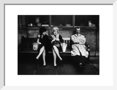 Two women and a man sit on a bench 1961