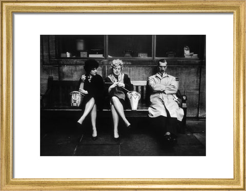 Two women and a man sit on a bench 1961