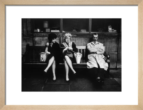 Two women and a man sit on a bench 1961