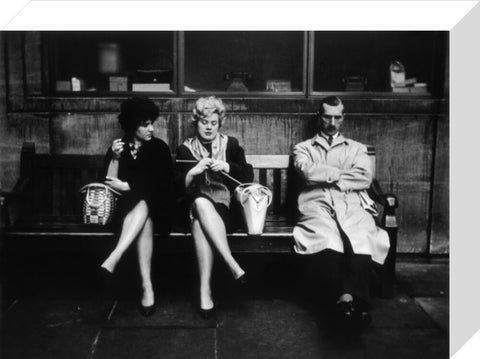 Two women and a man sit on a bench 1961