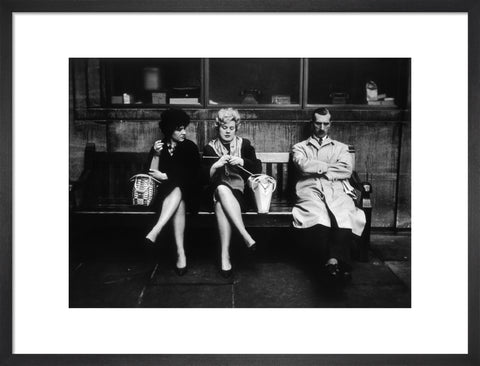 Two women and a man sit on a bench 1961