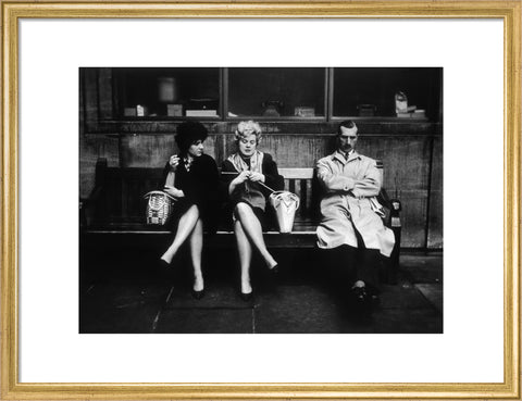 Two women and a man sit on a bench 1961