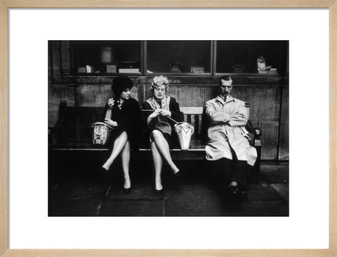 Two women and a man sit on a bench 1961
