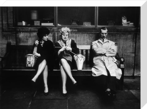 Two women and a man sit on a bench 1961
