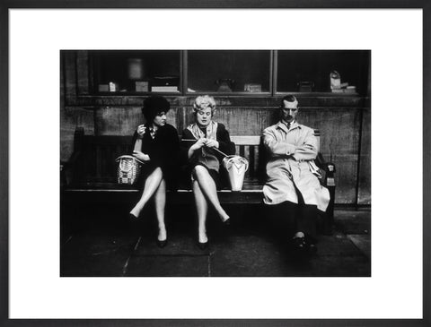 Two women and a man sit on a bench 1961
