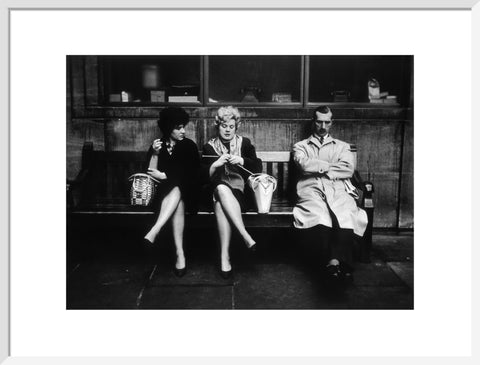 Two women and a man sit on a bench 1961