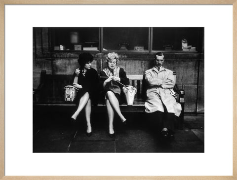 Two women and a man sit on a bench 1961