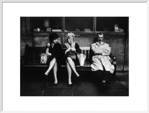 Two women and a man sit on a bench 1961