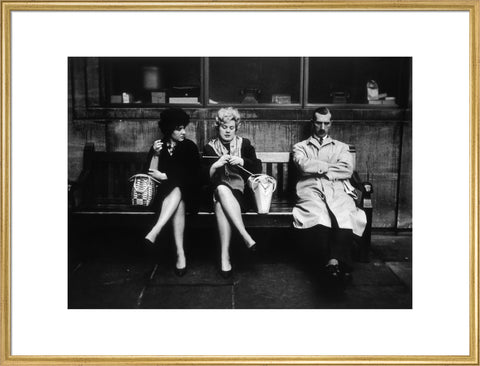 Two women and a man sit on a bench 1961