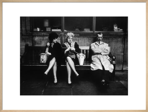 Two women and a man sit on a bench 1961