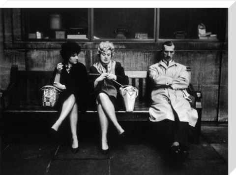 Two women and a man sit on a bench 1961