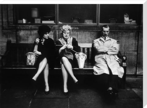 Two women and a man sit on a bench 1961