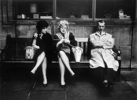 Two women and a man sit on a bench 1961