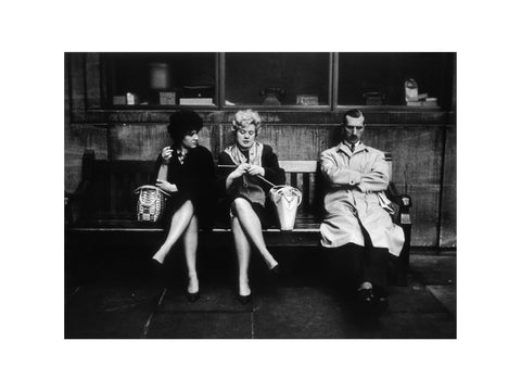 Two women and a man sit on a bench 1961