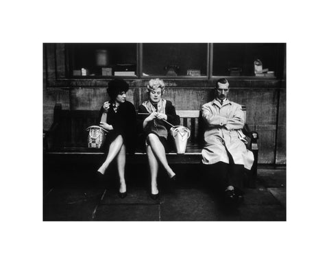 Two women and a man sit on a bench 1961