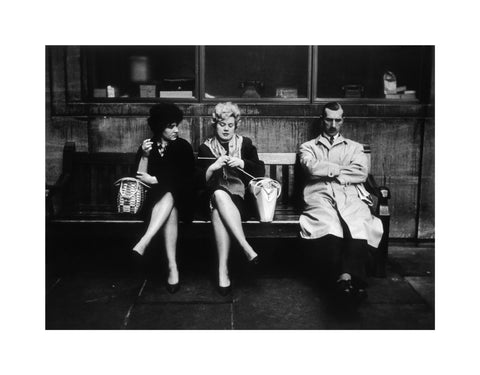 Two women and a man sit on a bench 1961