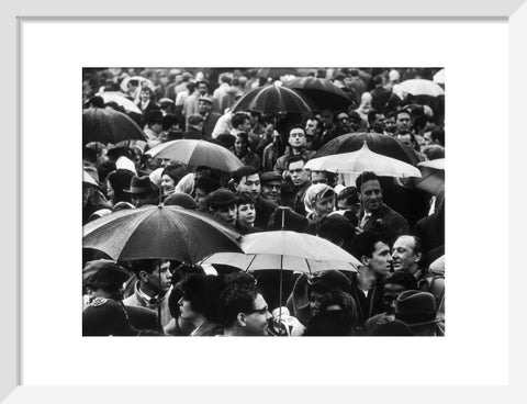 A crowd huddled underneath umbrellas in the rain 1961