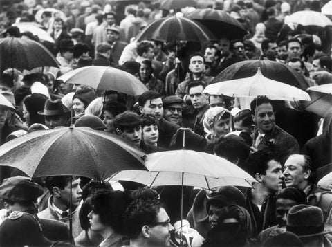 A crowd huddled underneath umbrellas in the rain 1961