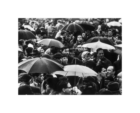 A crowd huddled underneath umbrellas in the rain 1961