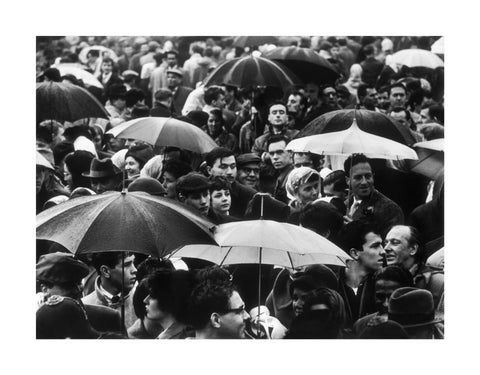 A crowd huddled underneath umbrellas in the rain 1961