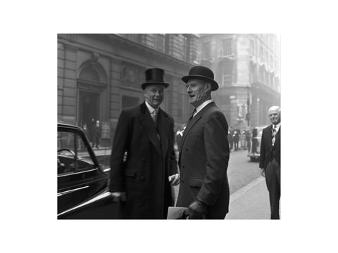 Three formally dressed men on a street flanked by high buildings. c.1955