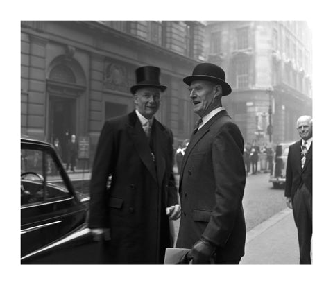 Three formally dressed men on a street flanked by high buildings. c.1955