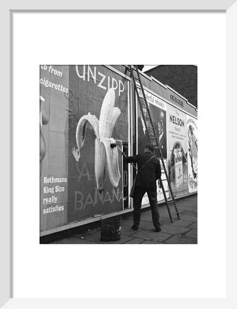 Man pastes up a billboard advertisement. c.1955