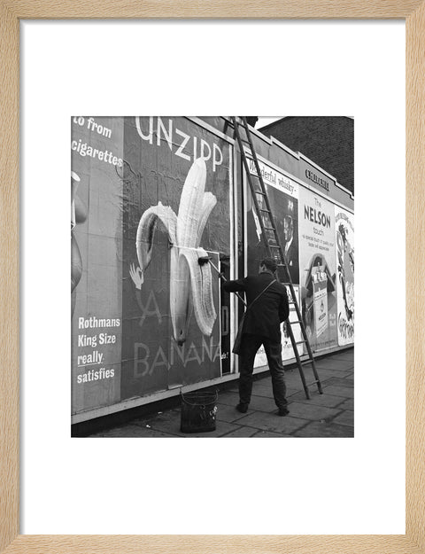 Man pastes up a billboard advertisement. c.1955