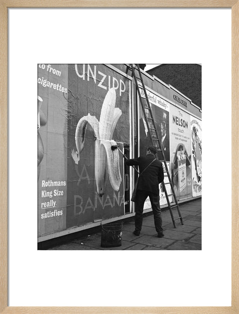Man pastes up a billboard advertisement. c.1955