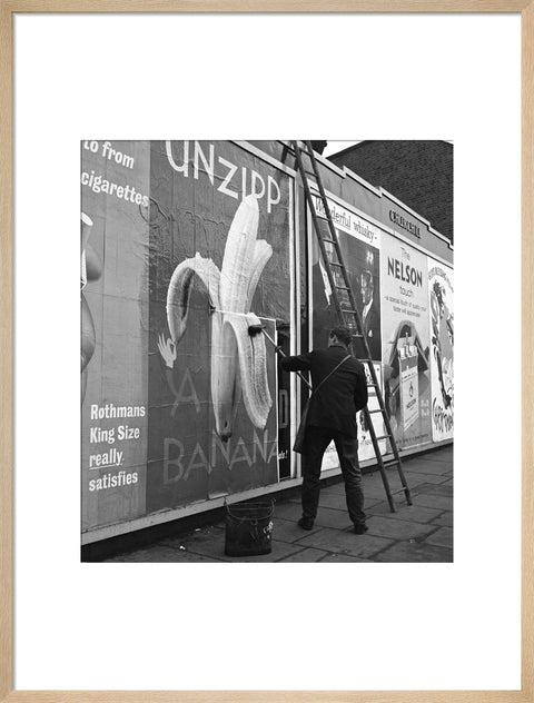Man pastes up a billboard advertisement. c.1955