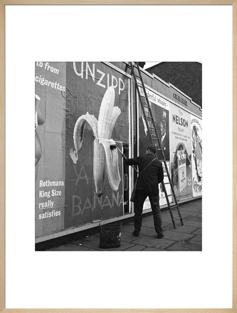 Man pastes up a billboard advertisement. c.1955