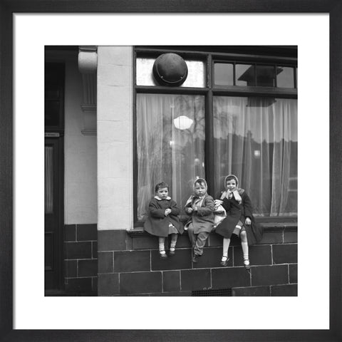 Three children perched on the windowsill of a pub. c.1955