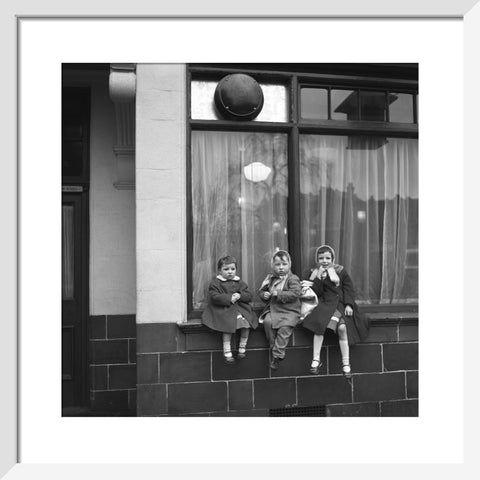 Three children perched on the windowsill of a pub. c.1955