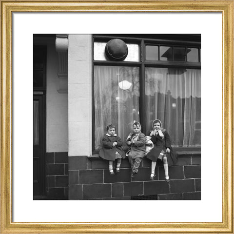 Three children perched on the windowsill of a pub. c.1955