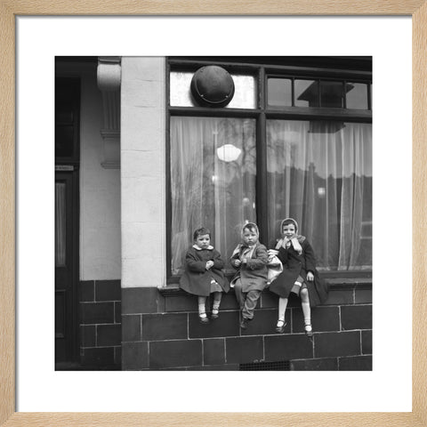 Three children perched on the windowsill of a pub. c.1955