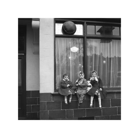 Three children perched on the windowsill of a pub. c.1955