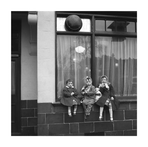 Three children perched on the windowsill of a pub. c.1955