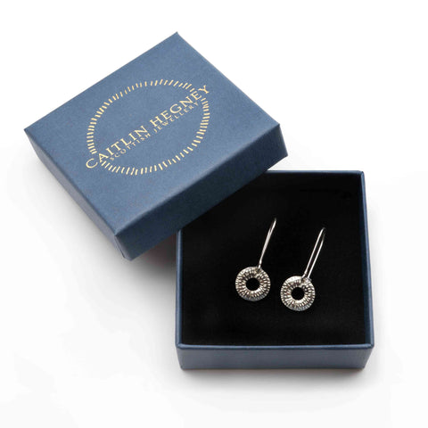 Silver earrings in a blue box with 'Caitlin Hegney' branding on a white background