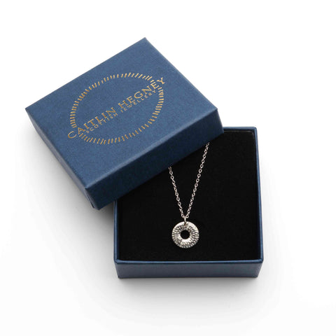 Silver necklace in an open blue box with 'Caitlin Hegney' branding' in golden letters