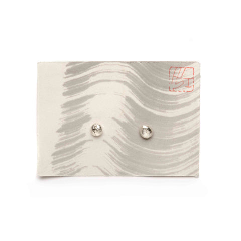Pair of irregular silver earrings on a wavy patterned card with a visible brand logo.