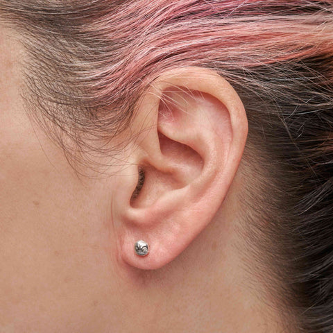 Close-up of a person with pink and brown hair wearing with a small silver stud earring.