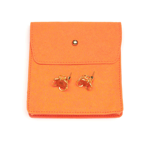 Pair of stud earrings with orange centres and gold frames on an orange jewellery pouch. 