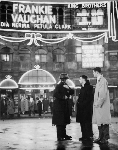 A group of men talking outside the Palace Theatre Shaftsbury Avenue c. 1955