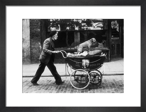 Man pushing a pram containing his wares and a standing dog 1961