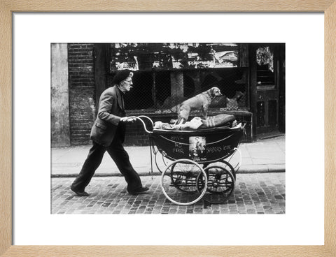 Man pushing a pram containing his wares and a standing dog 1961