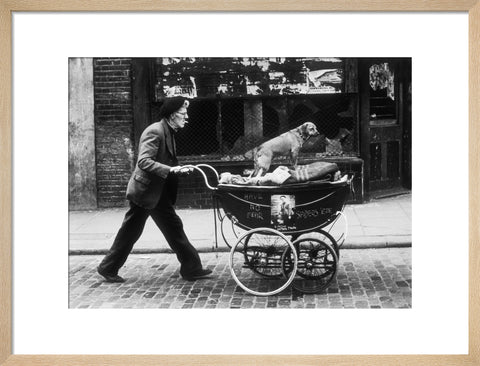 Man pushing a pram containing his wares and a standing dog 1961