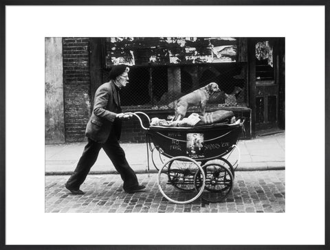 Man pushing a pram containing his wares and a standing dog 1961