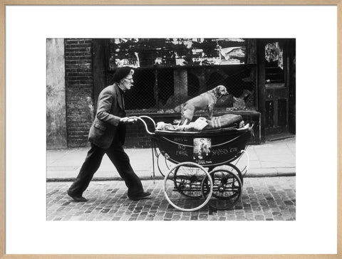 Man pushing a pram containing his wares and a standing dog 1961